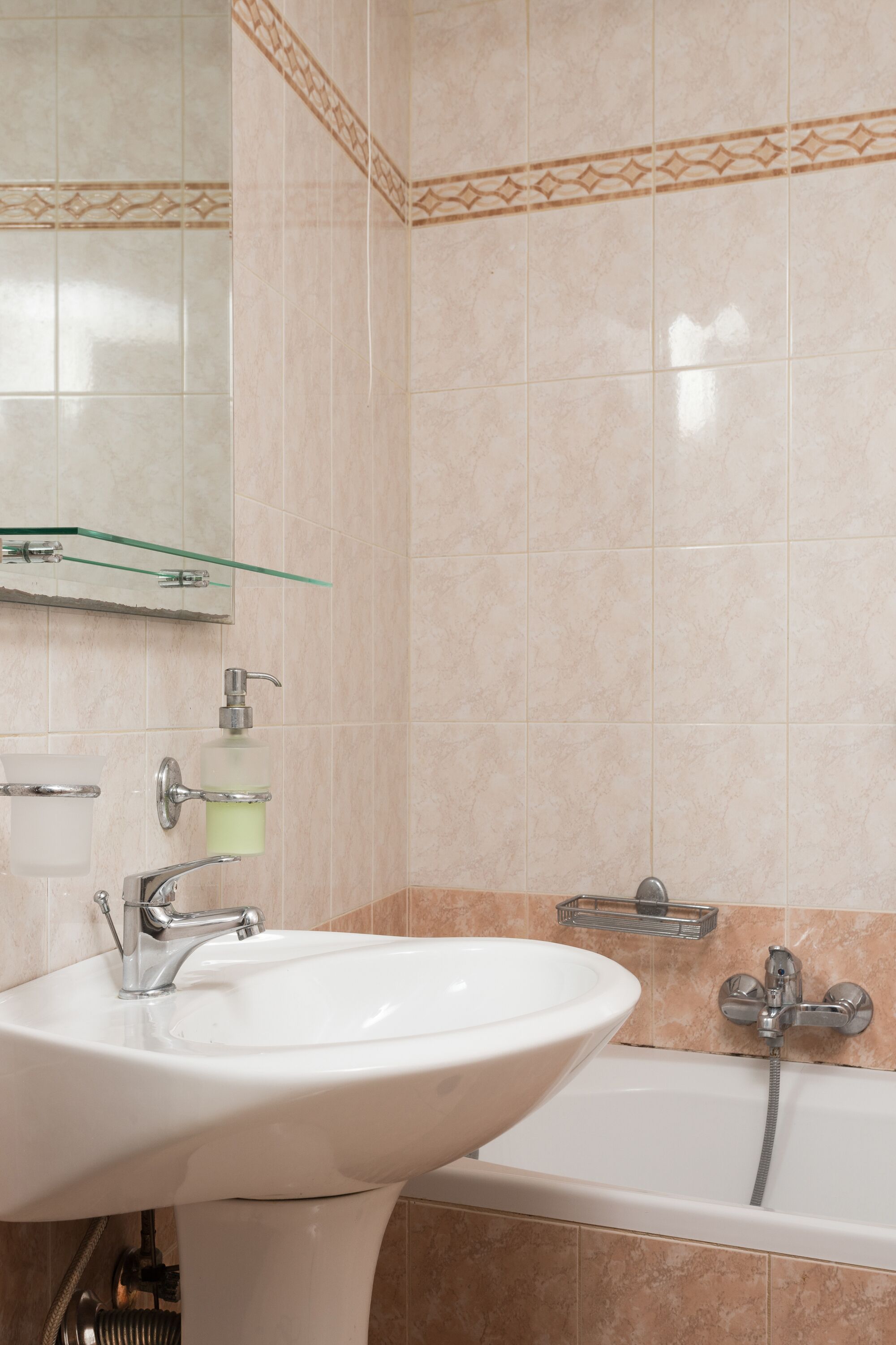 A bathroom with a sink, mirror, and bathtub.