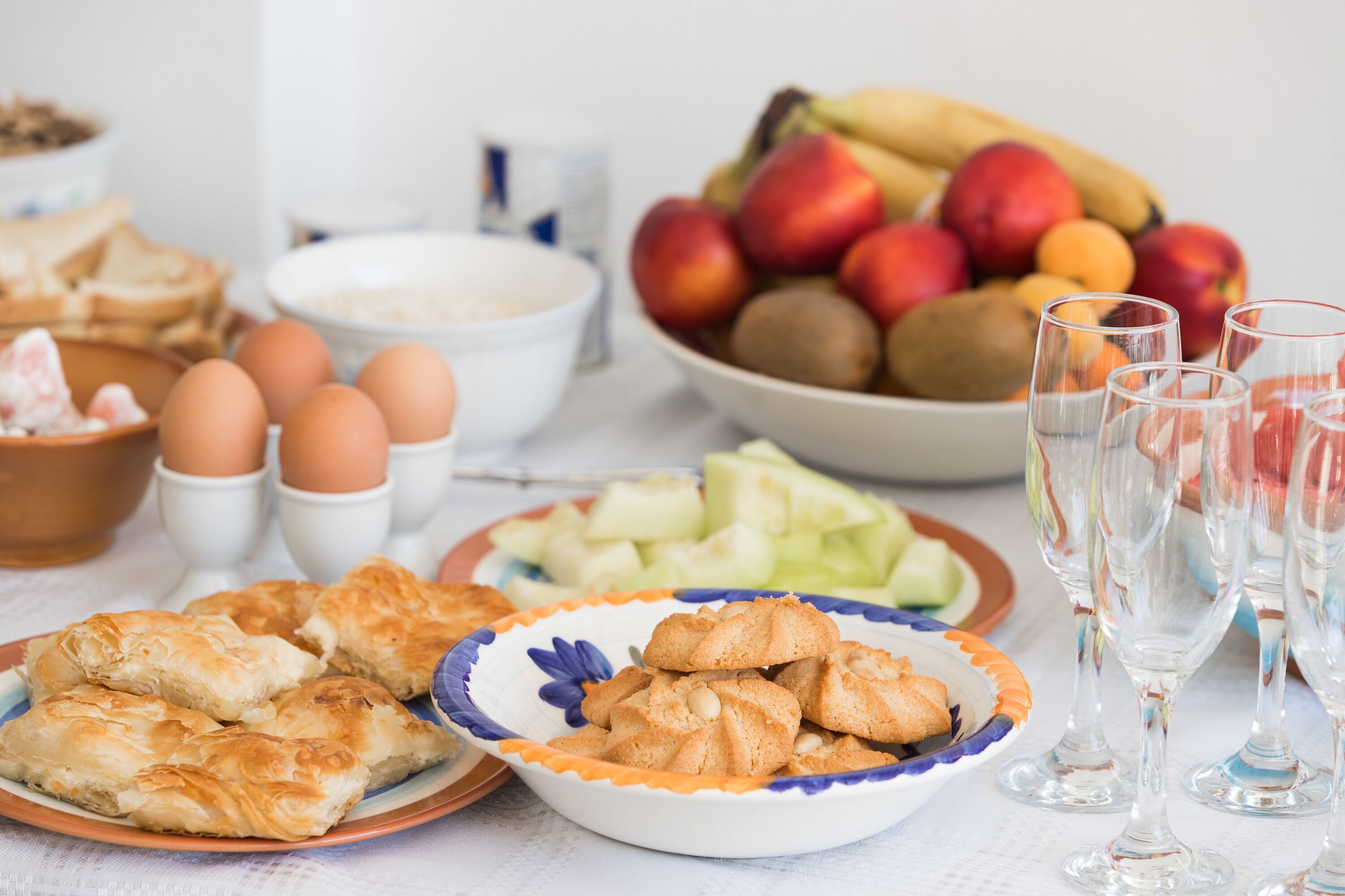 A table with food items including pastries, fruits, and eggs.