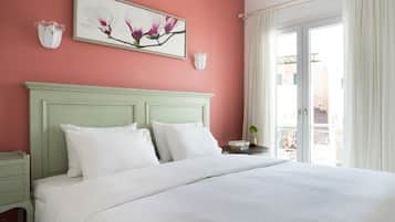 A bed with white bedding, a green headboard, and two white pillows. There is a framed picture of flowers on the wall above the bed.