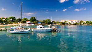 Un port de plaisance avec plusieurs bateaux amarrés, une eau calme et une ville côtière en arrière-plan.