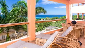 A balcony with wicker furniture and a view of the ocean.