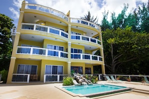 A multi-story hotel with balconies, a swimming pool, and outdoor seating.