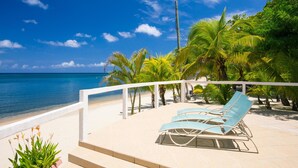 A beachside patio with lounge chairs and a view of the ocean. - Villa Del Playa 3 (Roatan)