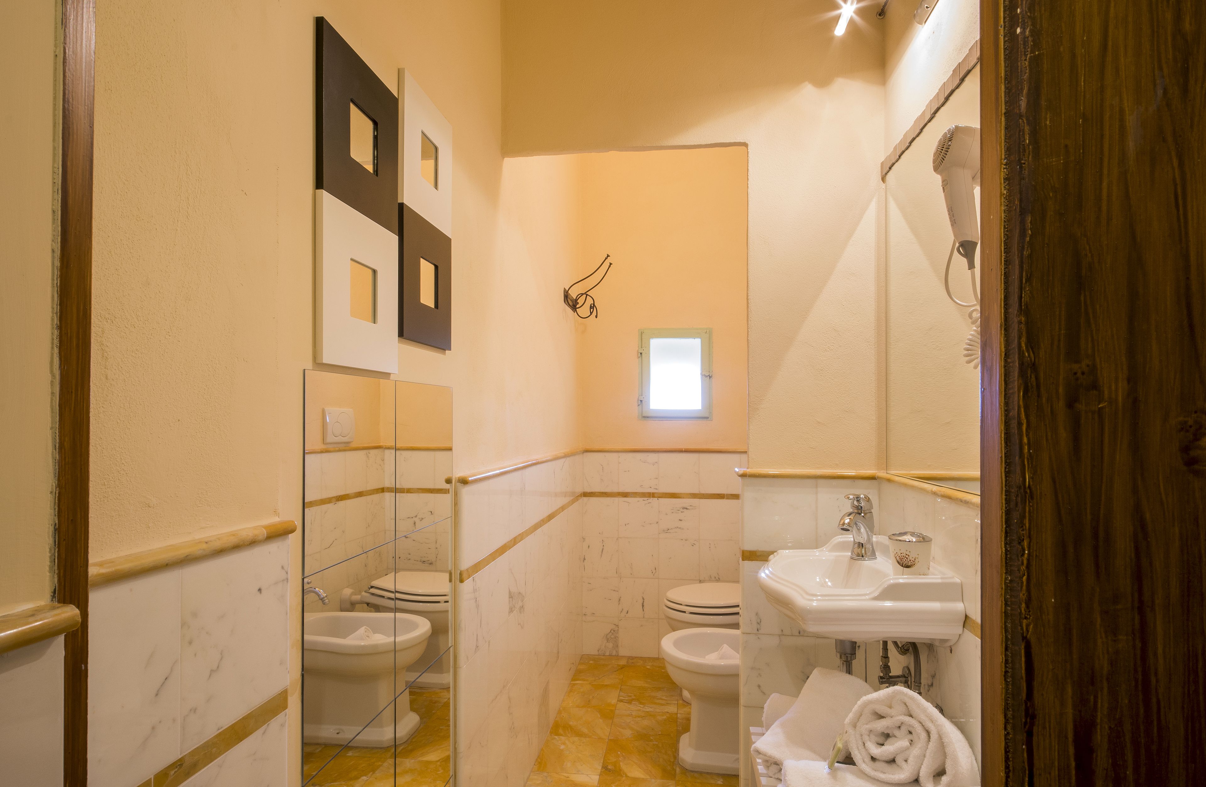 Une salle de bain avec deux toilettes, un lavabo et un sèche-cheveux.