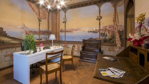 A room with a desk, chairs, a wooden table, and a mural of a cityscape. - Villa Sant Andrea (Siena)