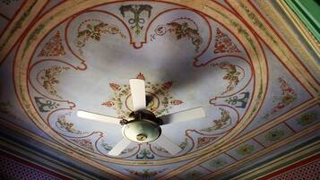 Un soffitto decorato con motivi floreali e una ventola a soffitto.