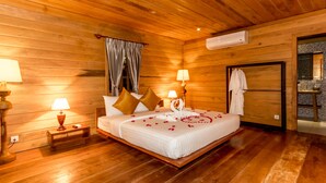 A wooden cabin-style bedroom with a bed, two bedside lamps, a nightstand, and a window with curtains. - Angkor Heart Bungalow (Siem Reap)