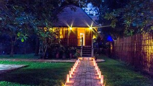 A house with a brick pathway leading to the entrance, surrounded by greenery and a bamboo fence. - Angkor Heart Bungalow (Siem Reap)