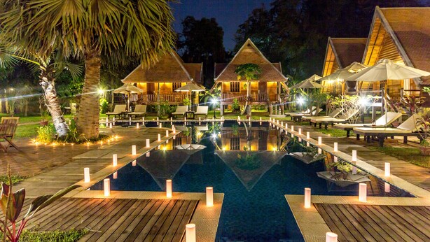 A nighttime resort with a central pool, wooden deck, and thatched-roof villas. - Angkor Heart Bungalow (Siem Reap)