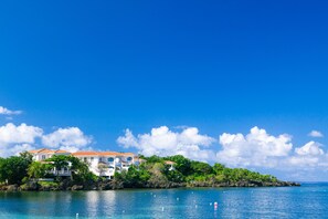 A coastal property with multiple buildings, a clear blue sky, and calm water.