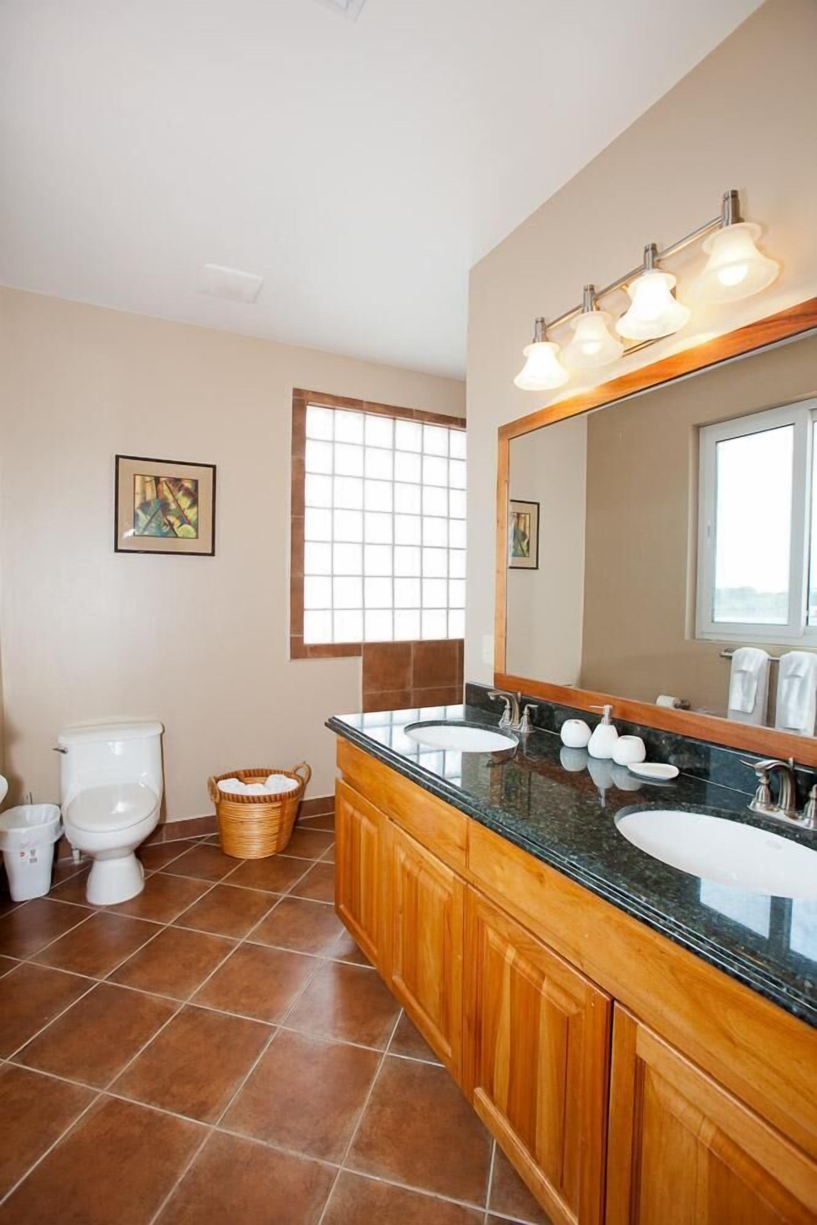 A bathroom with two sinks, a large mirror, and a window.