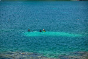 A clear view of a calm body of water with two people on a yellow raft. - Coral Vista 3 (Roatan)