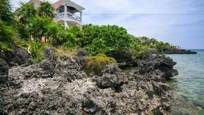A coastal property with a house surrounded by lush greenery and rocky terrain. - Coral Vista 3 2 bedroom option (Roatan)