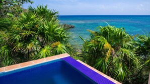 A clear view of a swimming pool with a view of the ocean and tropical vegetation. - Coral Vista 3 2 bedroom option (Roatan)