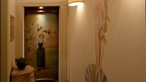 A hallway with wooden beams, a floral painting, a sculpture, and a patterned rug. - Relais A Ponte Pietra (Verona)