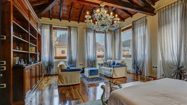 A spacious bedroom with a large bed, two sofas, and a chandelier. - Relais A Ponte Pietra (Verona)