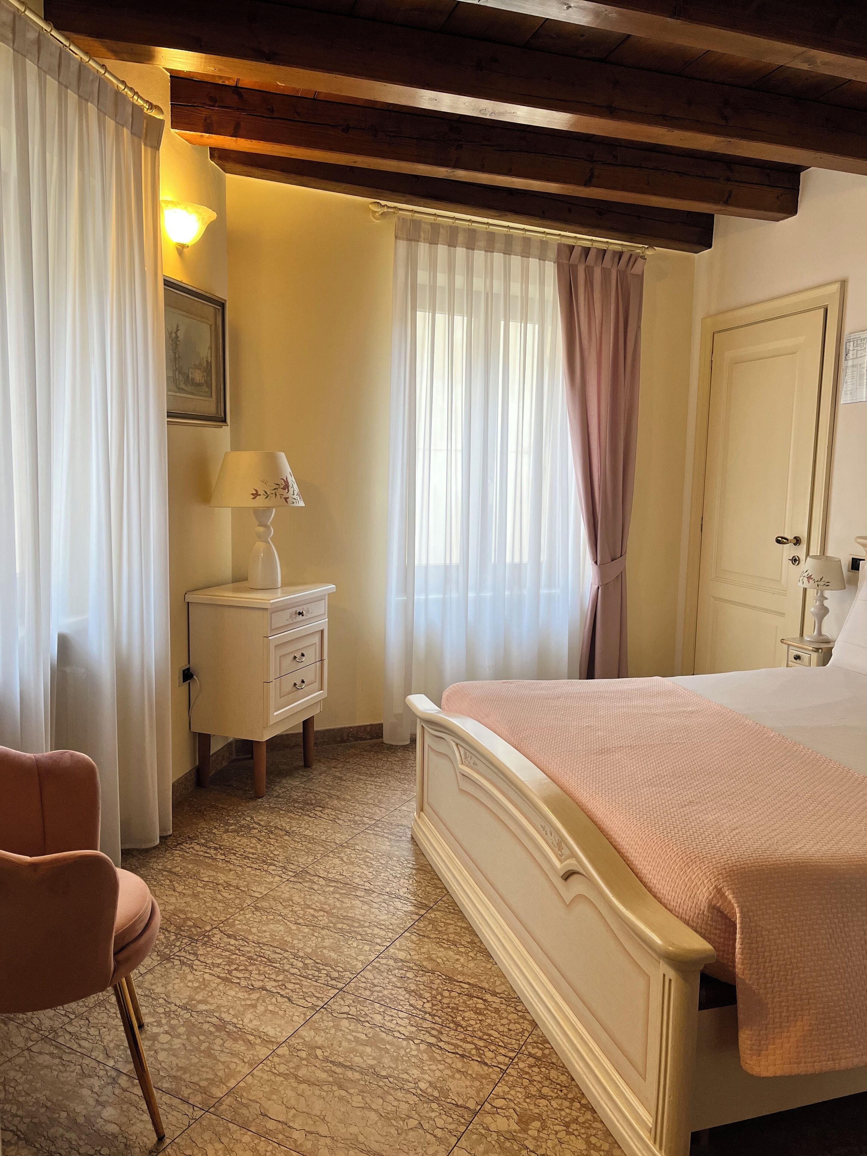 Une chambre à coucher avec un lit, une table de chevet, une chaise et une fenêtre avec des rideaux.