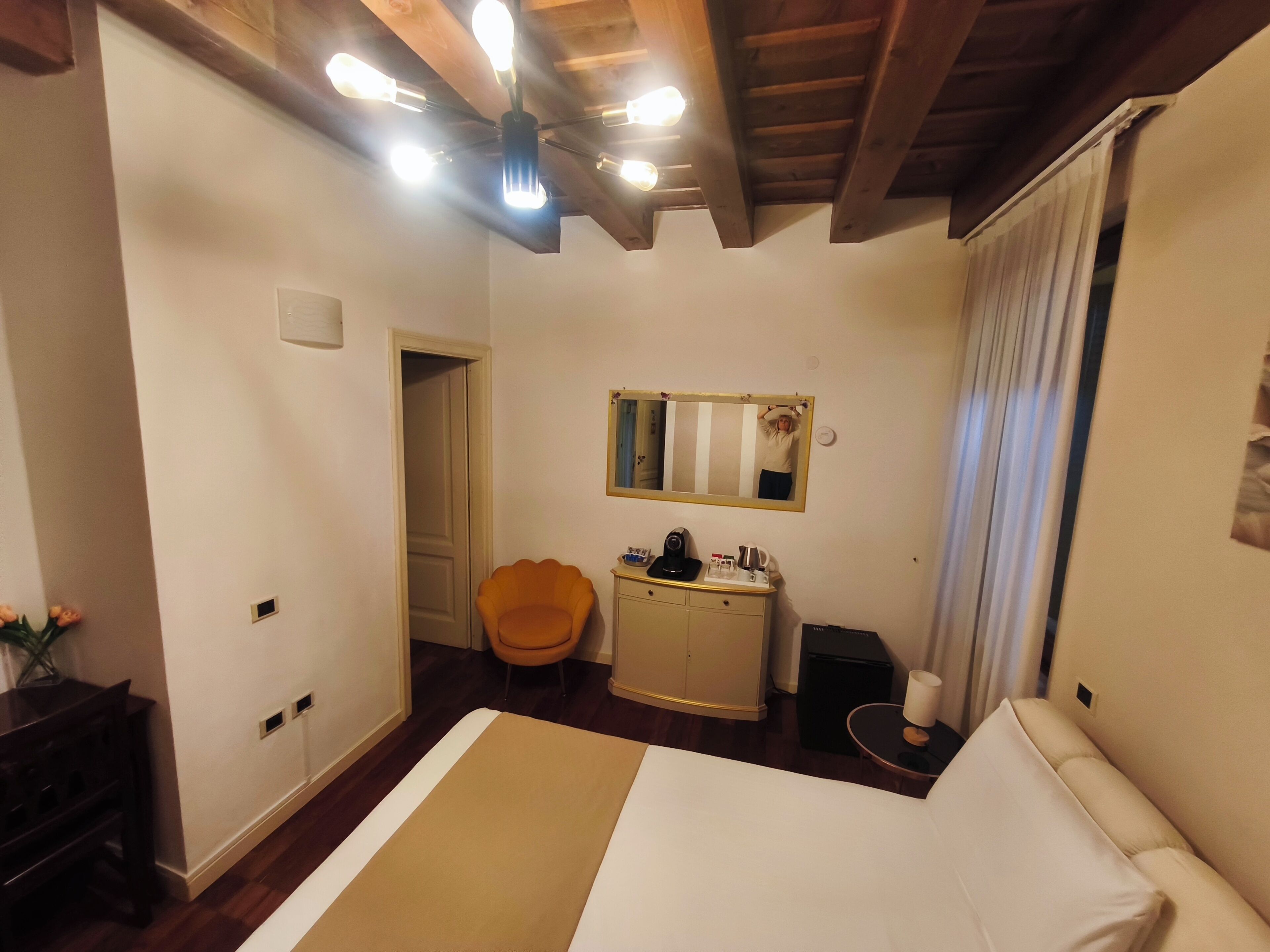 A bedroom with a bed, a chair, a dresser, a mirror, and a ceiling fan.