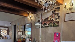 A reception area with a marble counter, a chandelier, and a wall-mounted sign. - Relais A Ponte Pietra (Verona)
