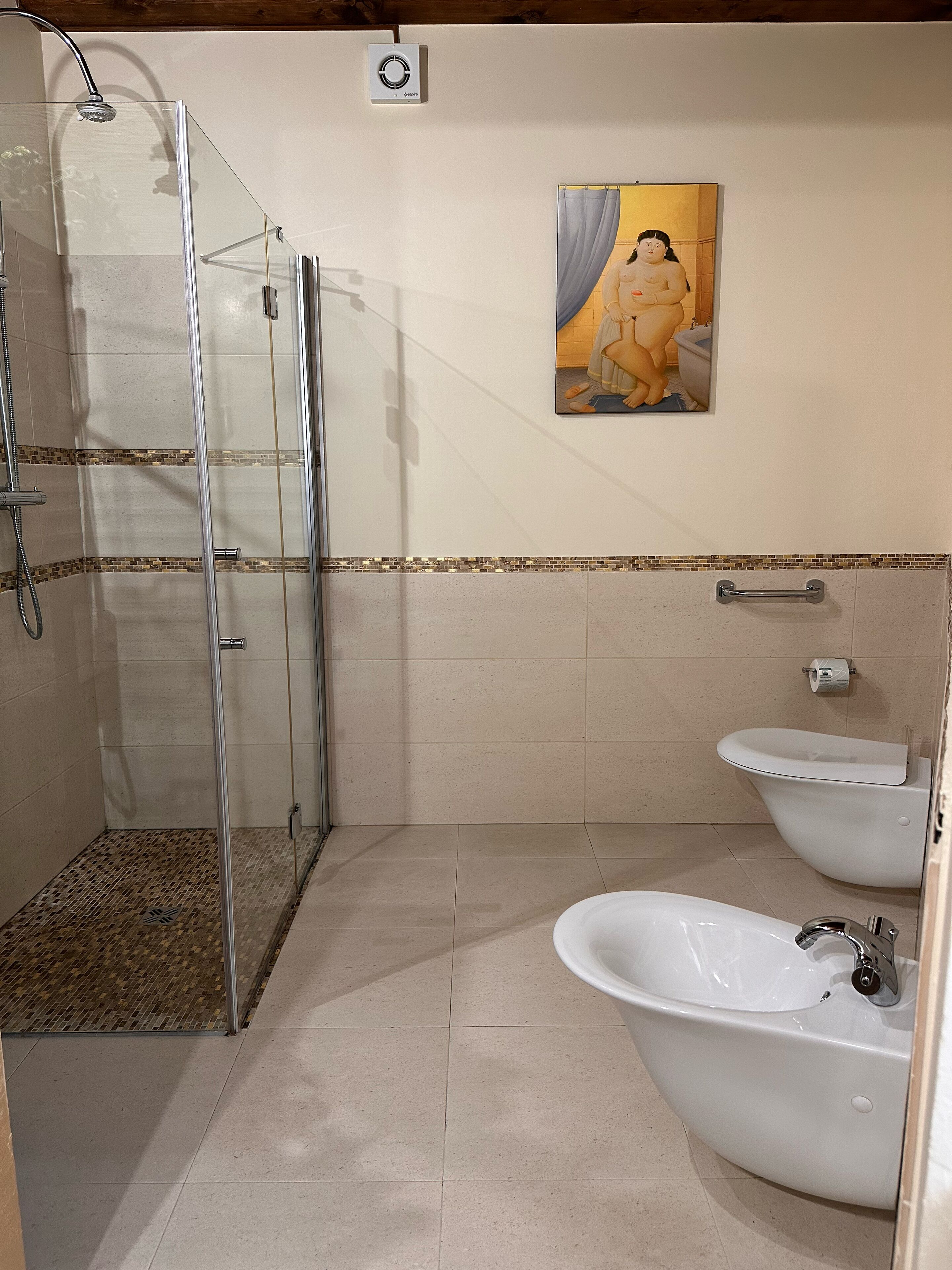 Un baño con cabina de ducha de vidrio, inodoro y lavamanos.