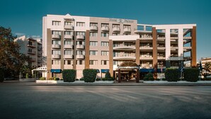 Un hotel de varios pisos con un diseño arquitectónico moderno, que cuenta con balcones y una entrada principal.