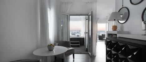 Une chambre d’hôtel moderne dotée d’un coin repas, offrant une vue sur le paysage urbain et comprenant un meuble aux motifs noirs.