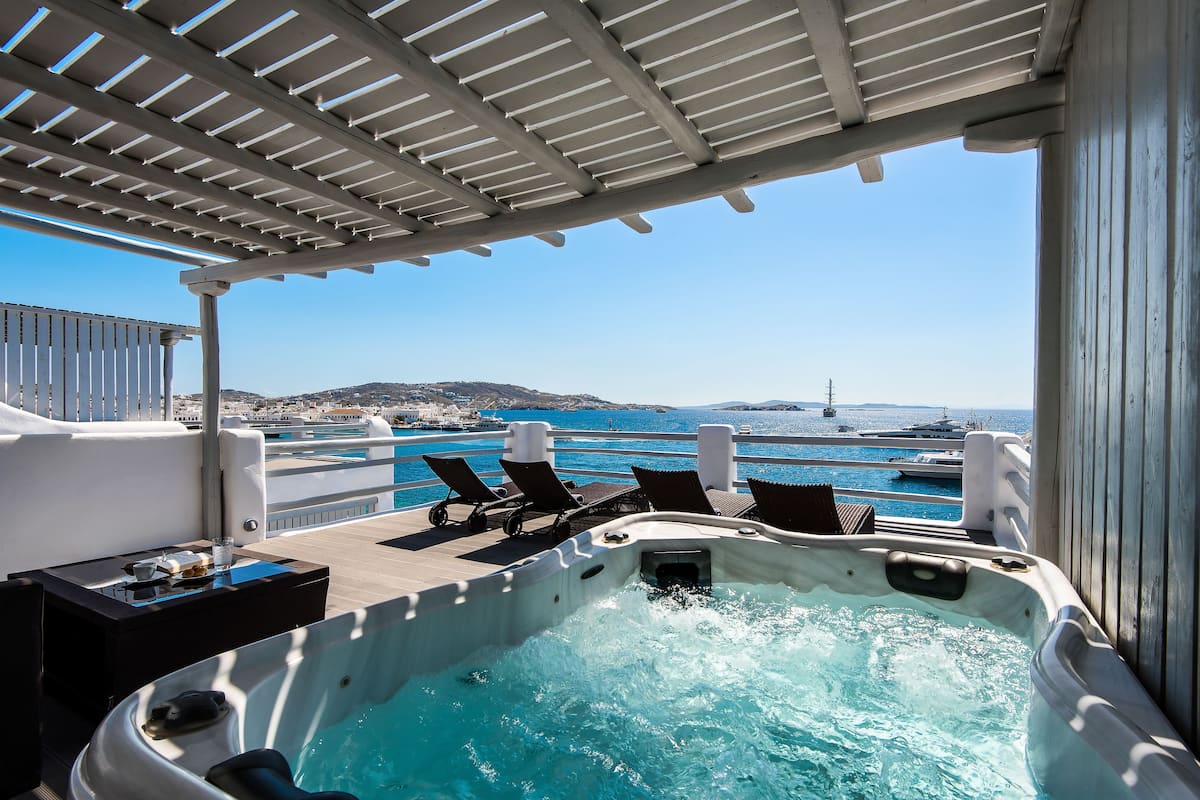 Un jacuzzi con vista al mar y una zona de piscina con sillones reclinables.