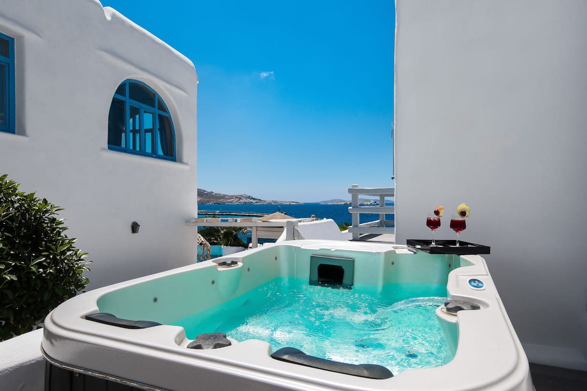 Un jacuzzi con vista despejada al mar y un edificio blanco con ventanas azules.