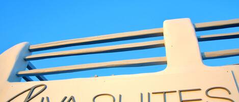 A sign for Riva Suites with a clear blue sky in the background.