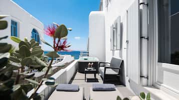 A balcony with a hot tub, seating, and a view of the sea.