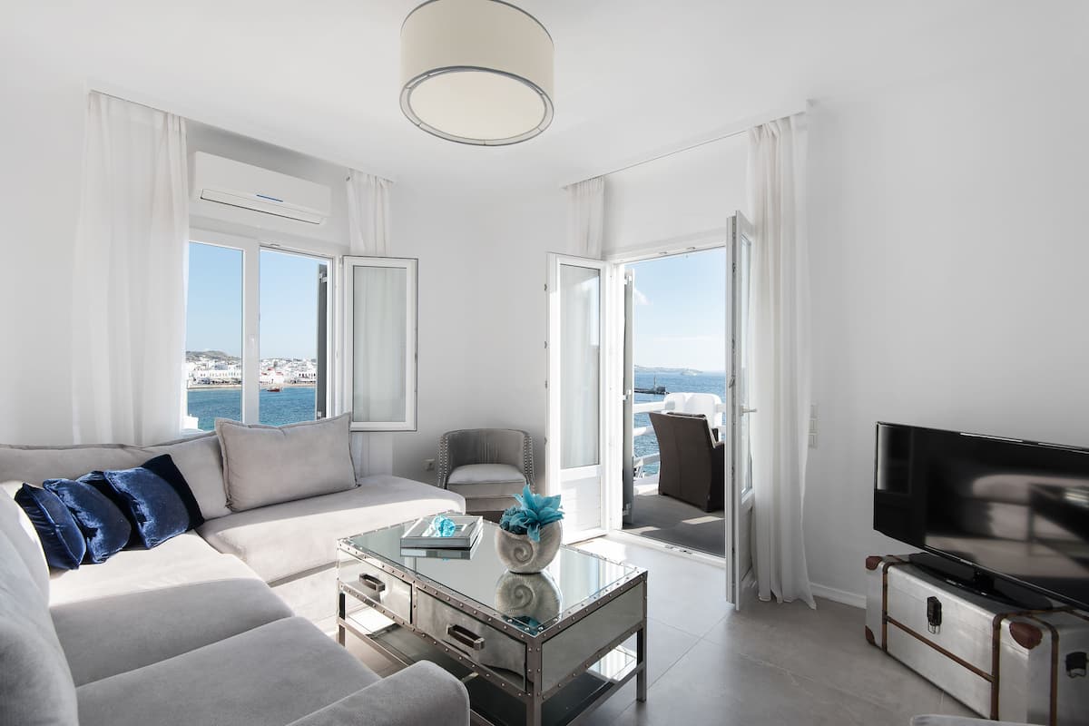 Una sala de estar moderna con un sofá, una mesa de centro, un televisor y vista al mar.