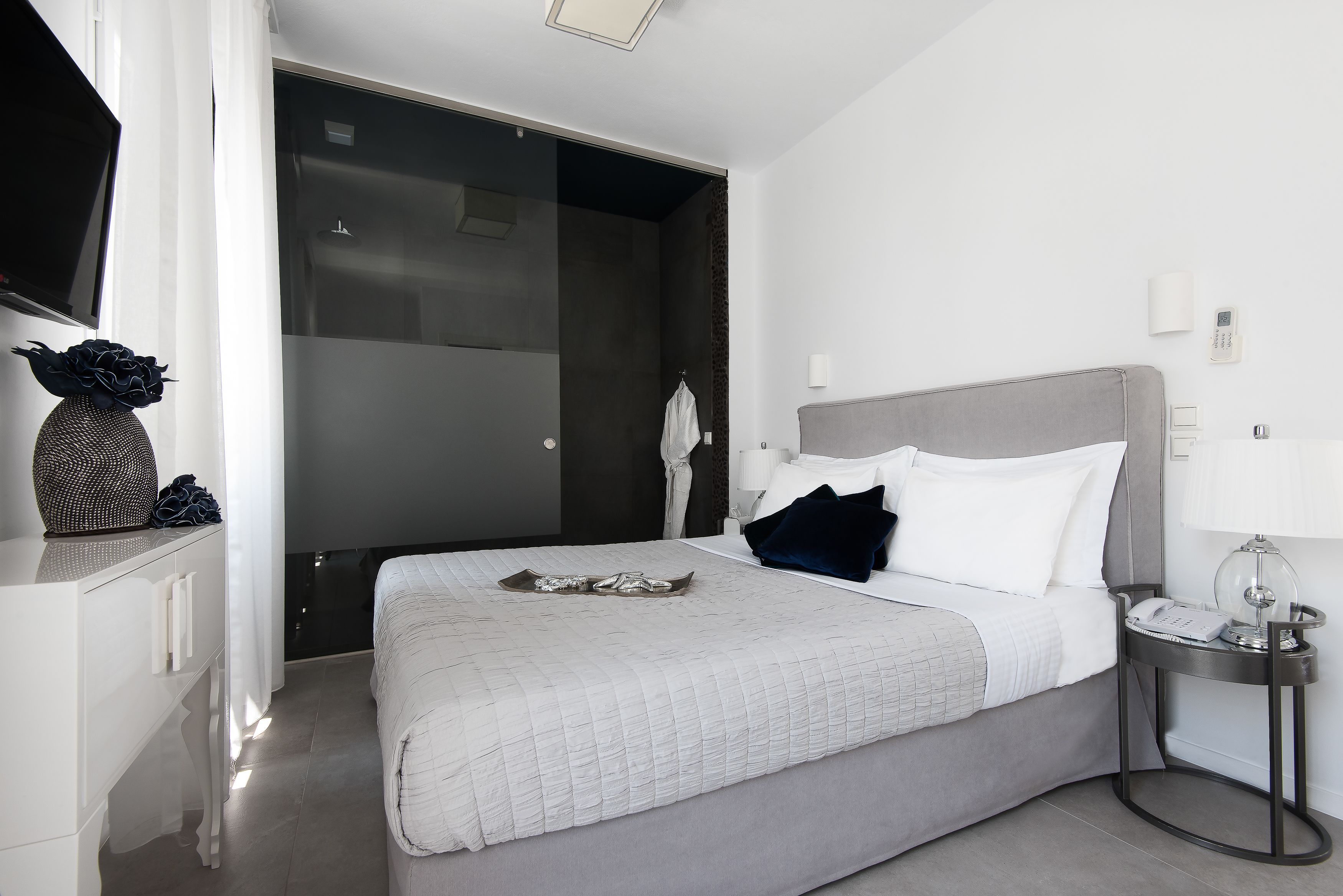 A modern bedroom with a large bed, bedside table, and a wardrobe.