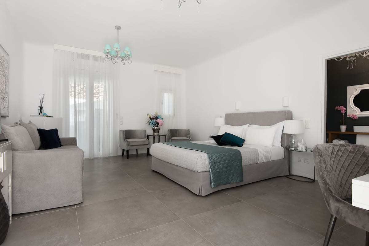 Un dormitorio moderno con cama, sofá, sillón y una mesita.