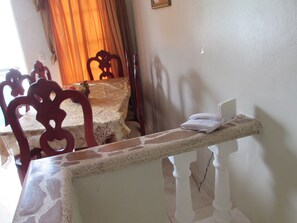 Un comedor con una mesa cubierta por un mantel estampado, sillas de madera y un teléfono blanco sobre una encimera.