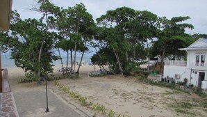Une vue sur la plage avec une promenade dallée, des chaises de plage et des parasols.