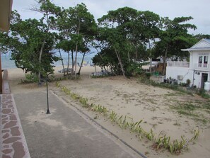 A beachside view with a paved walkway, beach chairs, and umbrellas.