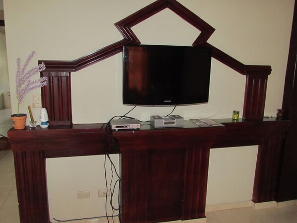 Un meuble de rangement en bois pour appareils multimédias, comprenant un téléviseur à écran plat, un lecteur DVD et une console de jeux.