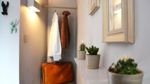 A hallway with a suitcase, two potted plants, and a towel hanging on a rack. - Monopoly Accommodations (London)