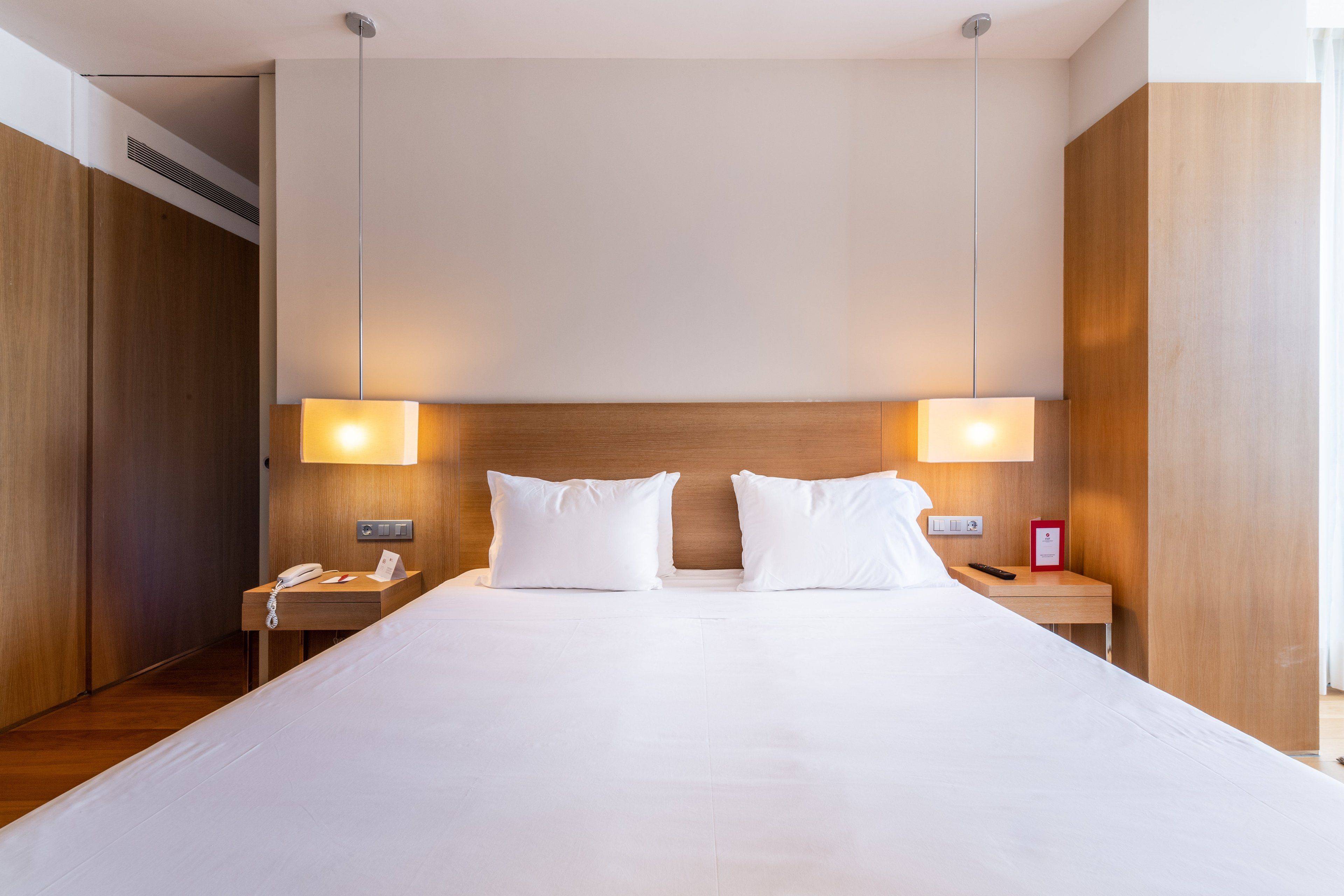 A hotel room with a large bed, two bedside tables, a phone, and a lamp.