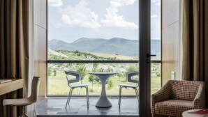 Ein Zimmer mit Blick auf Berge, ein Tisch mit zwei Stühlen und ein Sofa.