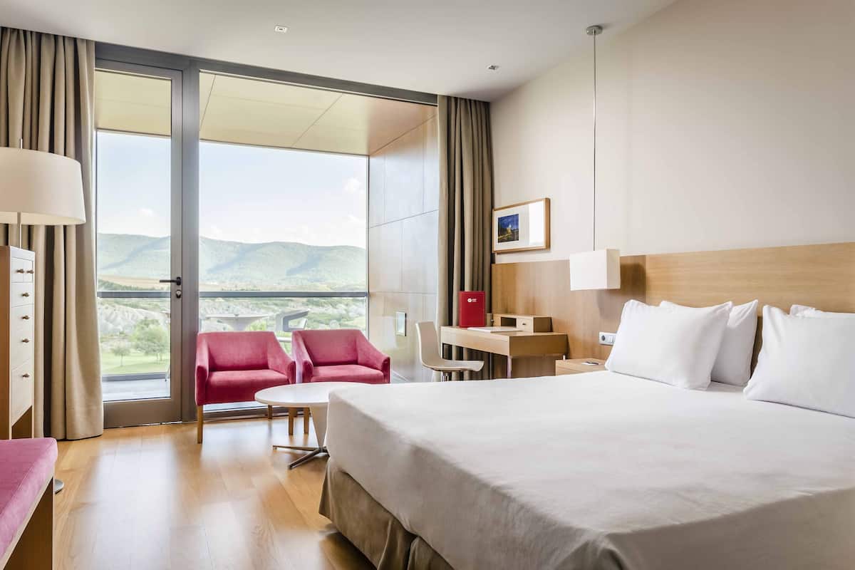 Una habitación de hotel con una cama grande, un escritorio, una silla y vistas al exterior.
