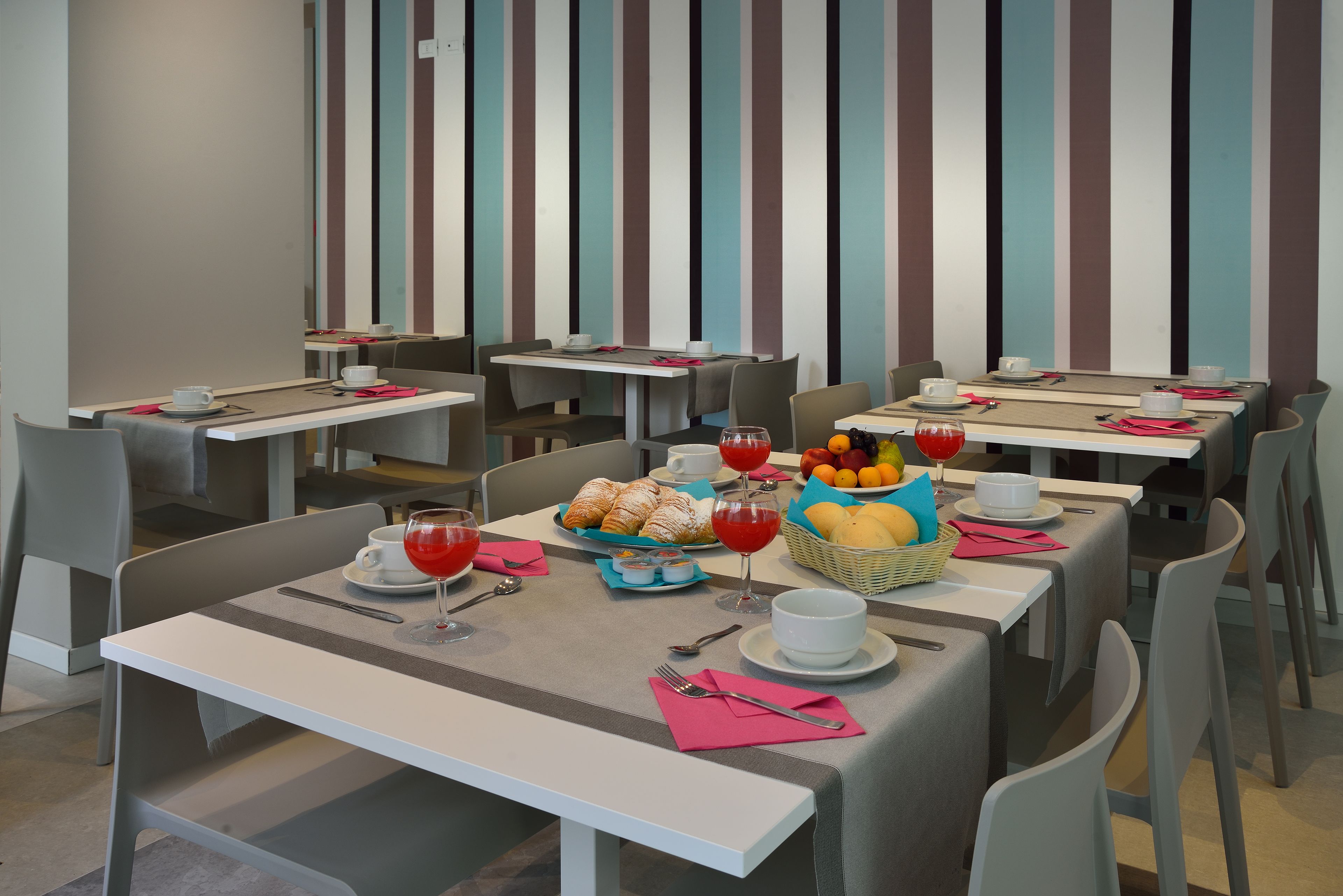 A modern dining area with striped walls, multiple tables, and chairs.