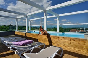 A rooftop pool area with lounge chairs and a woman relaxing by the pool. - Embassy Hotel & SPA (Cattolica)