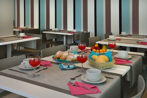 A dining area with tables set for breakfast, including croissants, fruit, and wine glasses. - Embassy Hotel & SPA (Cattolica)