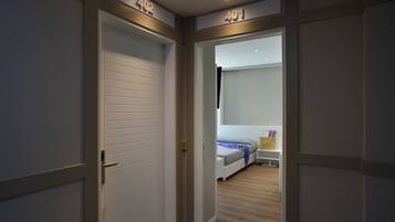 A hallway with doors labeled 402 and 401 leading to a bedroom with a bed, bedside table, and a nightstand.