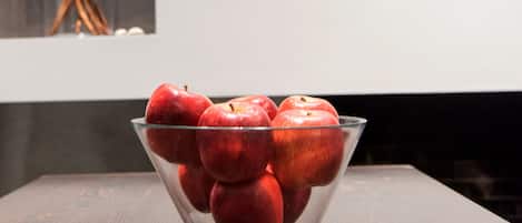 A clear glass bowl filled with red apples on a wooden table.