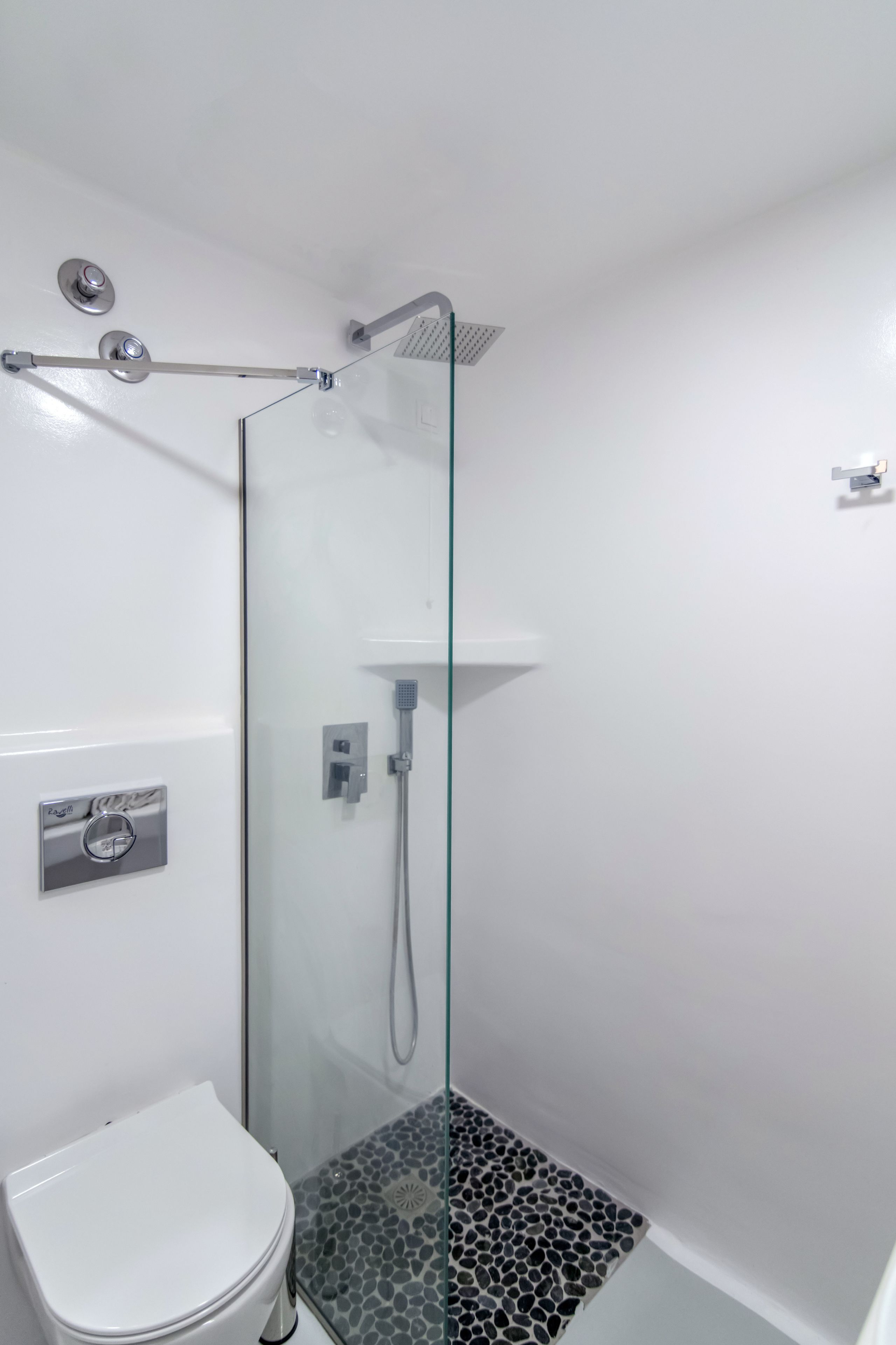 A bathroom with a glass-enclosed shower, a white toilet, and a patterned floor.