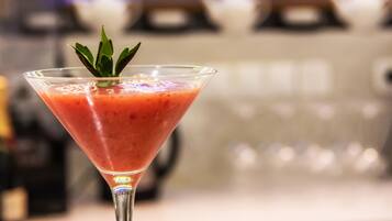 A martini glass with a strawberry drink on a bar counter.