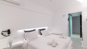 Habitación de hotel moderna con dos camas, una mesita de noche, una silla y la puerta del baño.