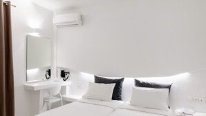 Een moderne hotelkamer met een groot bed, een bureau, een spiegel en een airconditioning.